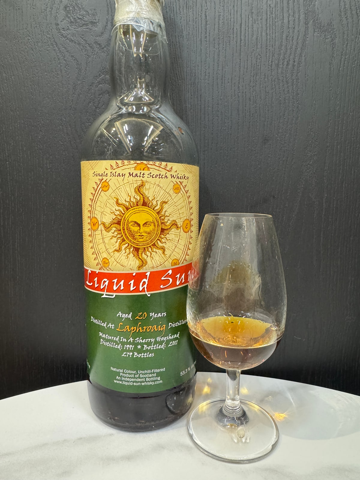 Illustrative image · Illustrative client photo: Liquid Sun Laphroaig 1991/2011, 20 years, 53.3%, with glass. The label says 279 bottles; it does not verify the review’s cask 279. Whole original frame; bottle top is cut off.